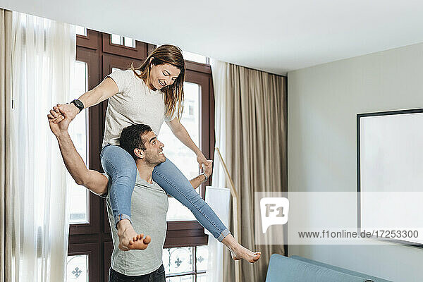 Playful man carrying woman on shoulders in hotel room