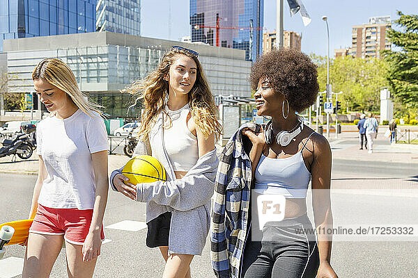 Weibliche Freunde unterhalten sich bei einem Spaziergang auf der Straße an einem sonnigen Tag