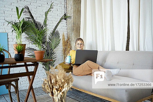 Geschäftsfrau  die einen Laptop benutzt  während sie zu Hause auf dem Sofa sitzt