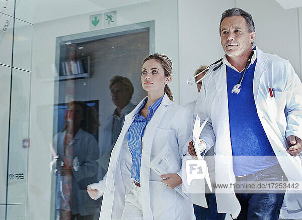 Weibliche und männliche Ärzte  die während eines Notfalls im Krankenhaus auf dem Korridor laufen