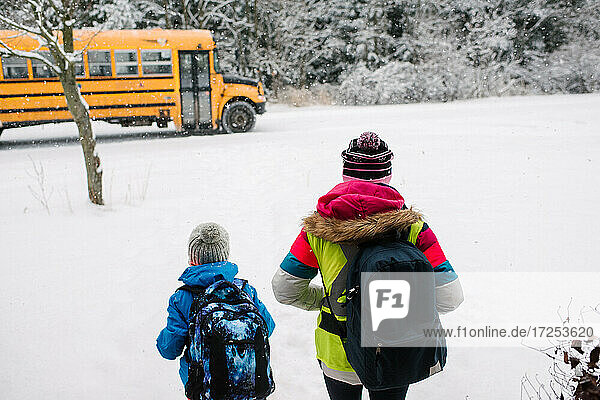 Canada  Ontario  Rear view of children walking towards school bus in snow