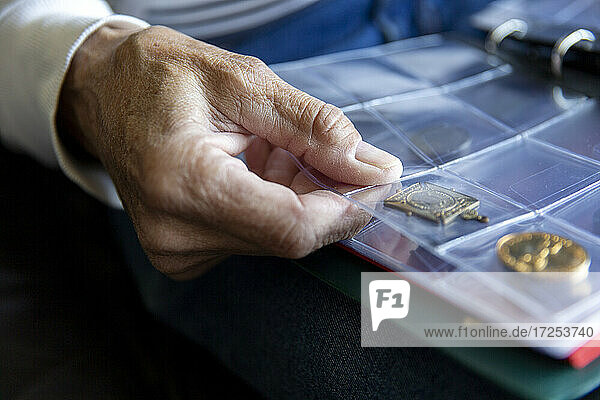 UK  East Sussex  Close-up of senior mans hand holding coin album
