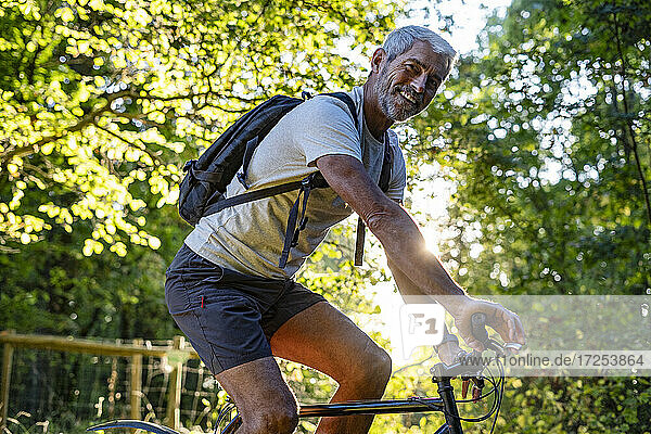 Portrait of smiling mature man cycling in forest