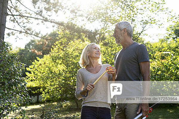 Lächelndes reifes Paar mit Gartengeräten im Hinterhof stehend