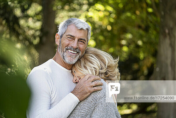 Lächelndes reifes Paar umarmt sich im Hinterhof