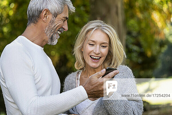 Glückliches reifes Paar benutzt Smartphone im Hinterhof