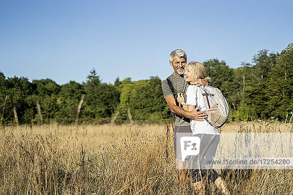 Smiling mature couple embracing while hiking in forest
