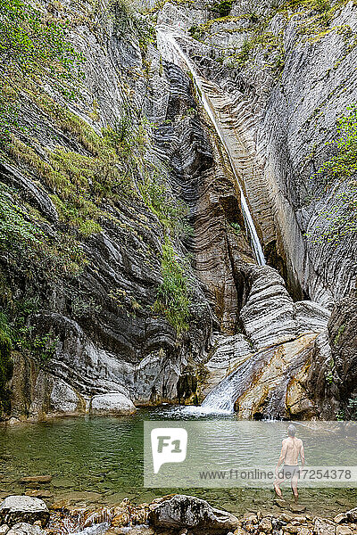 France  Alpes-de-Haute-Provence  Man in pond looking at waterfall on eroded rock