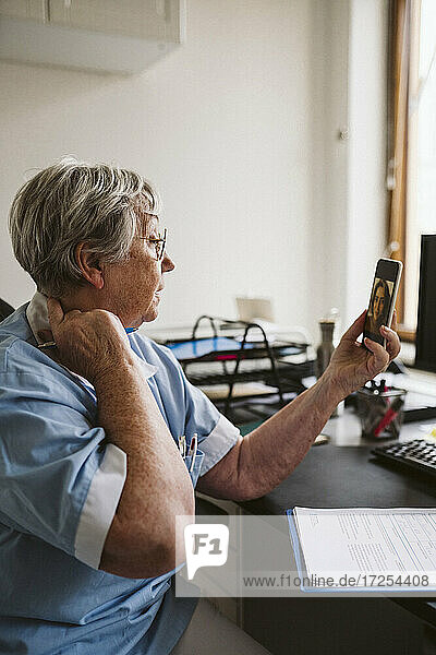 Ältere Ärztin berät Patienten per Videoanruf in einer medizinischen Klinik