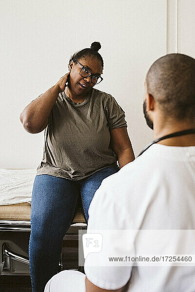 Mid erwachsene Frau Beratung mit männlichen Arzt über Nackenschmerzen in der medizinischen Klinik