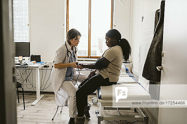 Weibliche Mitarbeiterin im Gesundheitswesen misst den Blutdruck eines jungen Patienten in einer medizinischen Klinik