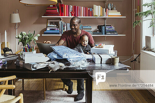 Lächelnde Geschäftsmann mit Laptop während der Arbeit im Büro zu Hause