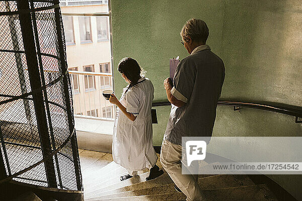 Weiblicher Arzt und Oberschwester bewegen sich die Treppe in der medizinischen Klinik hinunter