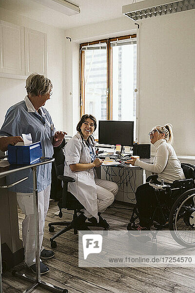 Volle Länge von fröhlichen weiblichen Arzt und behinderte Frau Blick auf ältere Krankenschwester in der medizinischen Klinik