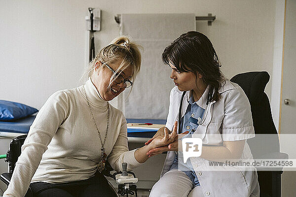 Weiblicher medizinischer Experte prüft den Puls eines behinderten Patienten in einer medizinischen Klinik