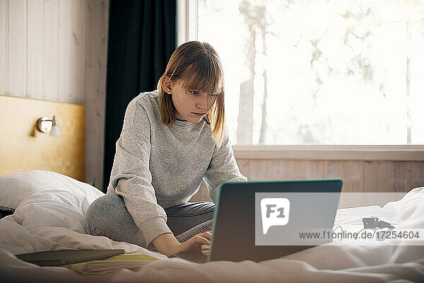 Teenager-Mädchen mit Laptop während der Hausaufgaben im Schlafzimmer