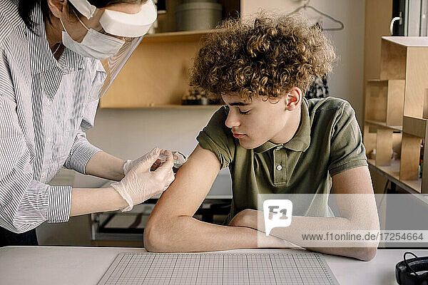Junge mit lockigen braunen Haaren Blick auf Krankenschwester Injektion Medizin zu Hause