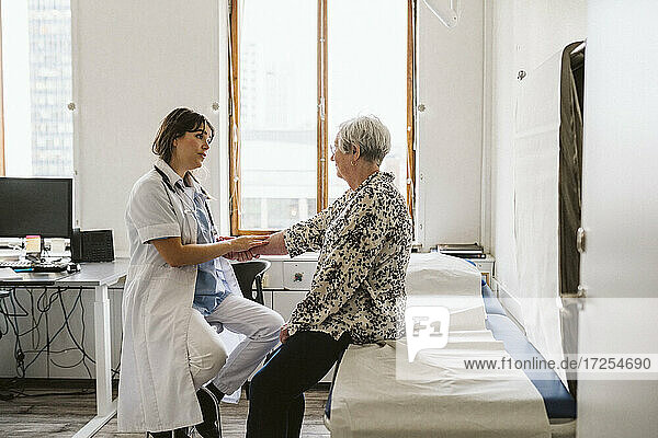 Ärztin prüft den Puls eines älteren Patienten in einer medizinischen Klinik