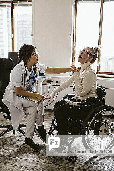 Ärztin untersucht behinderten Patienten im Rollstuhl sitzend in medizinischer Klinik