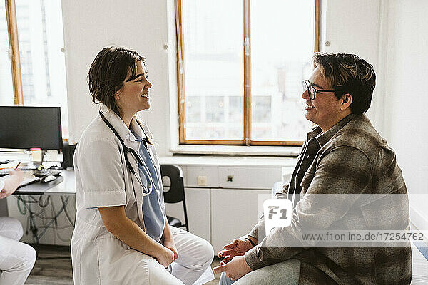 Smiling female doctor and male patient discussing while consulting at medical clinic