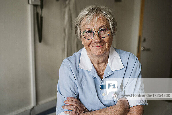 Porträt eines älteren weiblichen medizinischen Experten mit verschränkten Armen