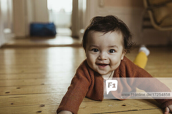 Portrait of smiling male toddler lying on floor at home