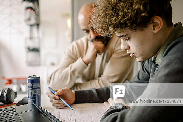 Junge macht Hausaufgaben  während er bei seinem Vater zu Hause sitzt