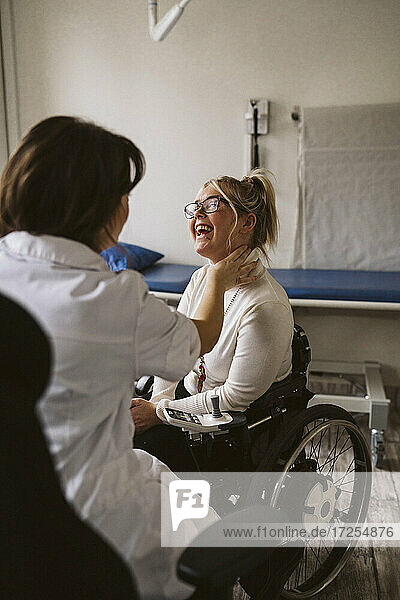 Weiblicher medizinischer Experte prüft den Puls einer lächelnden behinderten Frau in einer medizinischen Klinik