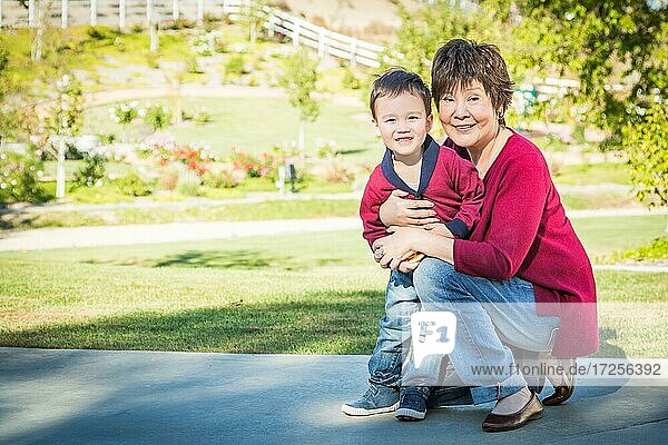 Glückliche chinesische Großmutter hat Spaß mit ihrem gemischtrassigen Enkel draußen