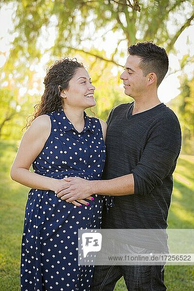 Happy hispanic man with his pregnant wife outdoors at the park