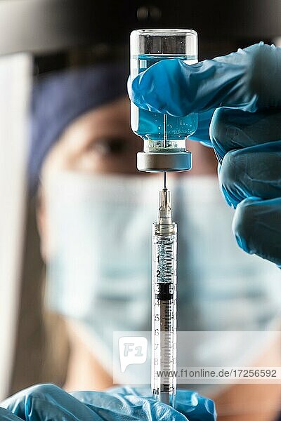Arzt oder Krankenschwester mit chirurgischen Handschuhen hält Impfstoffampulle und medizinische Spritze