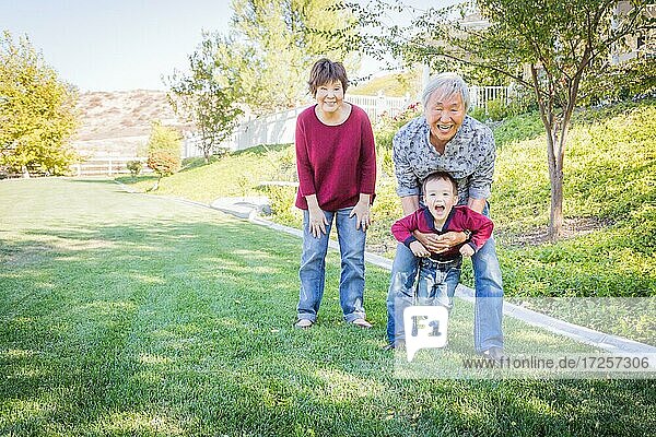 Glückliche chinesische Großeltern haben Spaß mit ihrem gemischtrassigen Enkel draußen