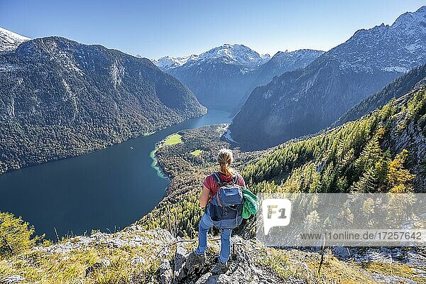 Panoramic view of the Königssee from the Rinnkendlsteig  young woman hiking to the Achenkanzel  autumnal forest and snow covered mountains  Berchtesgaden National Park  Berchtesgadener Land  Upper Bavaria  Bavaria  Germany  Europe