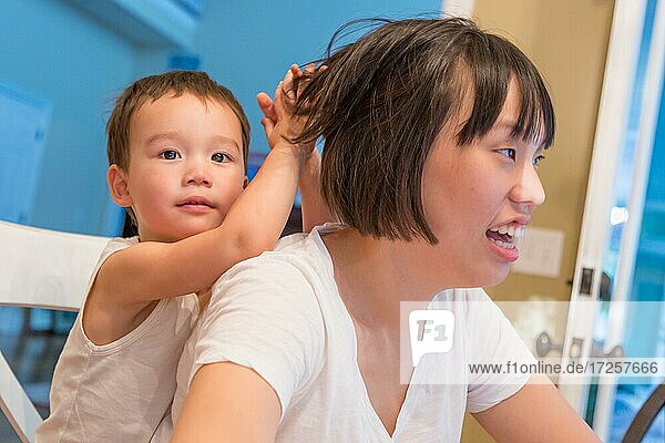 Glücklicher chinesisch und kaukasisch gemischtrassiger Jungen hat Spaß mit chinesischer Mutter im Haus
