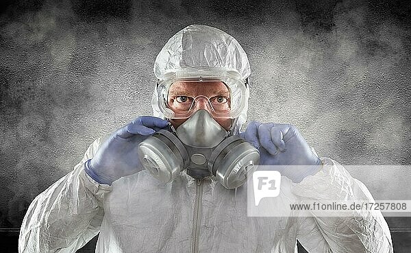 Man wearing hazmat suit  goggles and gas mask is smokey dark room