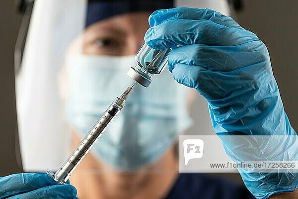 Arzt oder Krankenschwester mit chirurgischen Handschuhen hält Impfstoffampulle und medizinische Spritze