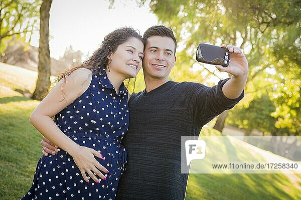 Schwangere Frau und Ehemann machen Selfie im Freien im Park