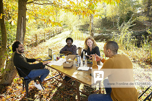 Geschäftsleute treffen und essen am Tisch im sonnigen Herbst Park