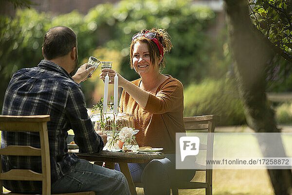 Glückliches Paar  das sich am sonnigen Gartentisch bindet