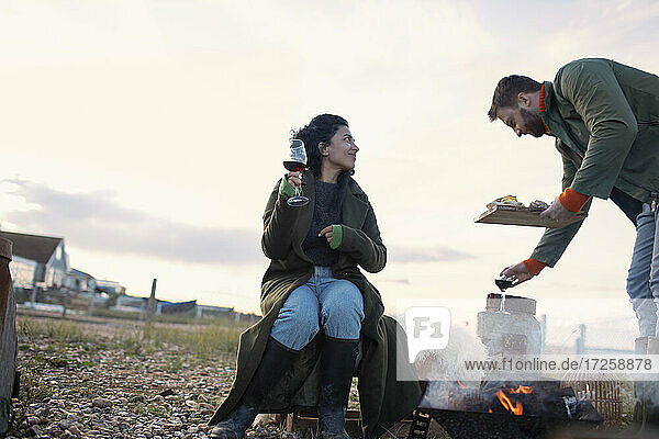 Paar genießt Wein am Feuer auf der Terrasse