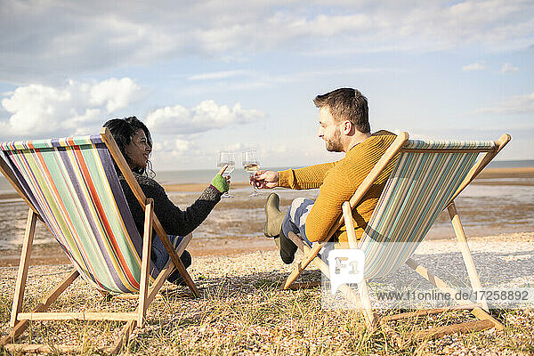 Glückliches Paar Toasting Weingläser auf sonnigen Winter Strand
