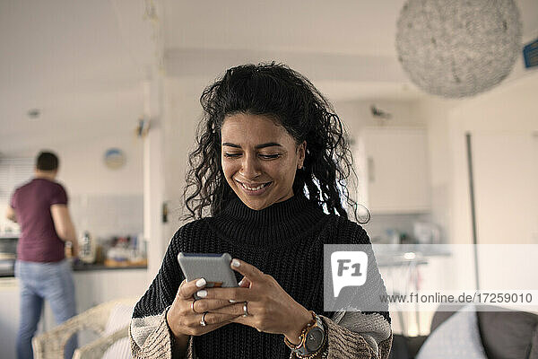 Glückliche Frau verwendet Smartphone zu Hause
