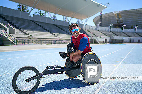 Portrait confident male wheelchair athlete on sunny blue sports track