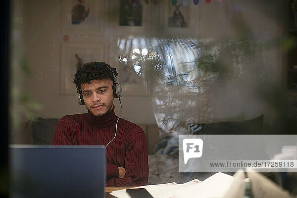 Konzentrierter junger Mann arbeitet nachts am Laptop im Heimbüro