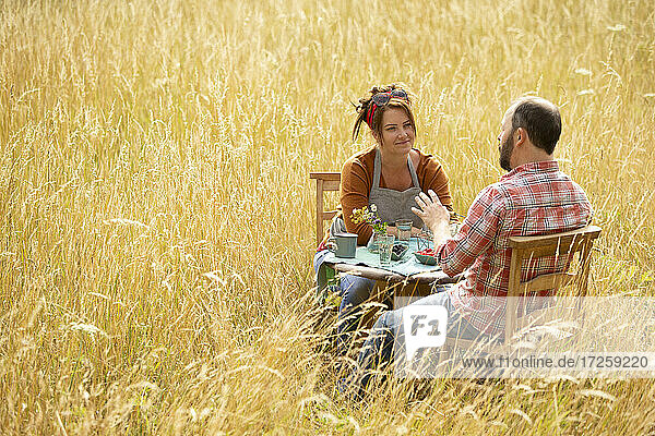 Paar im Gespräch und Essen Beeren am Tisch in sonnigen hohen Gras