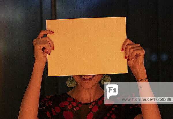 Porträt lächelnde Frau bedeckt Gesicht mit leeren Stück Papier