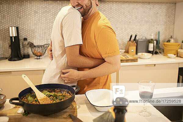 Glückliche Homosexuell männliches Paar Kochen und Umarmen in der Küche