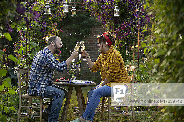 Glückliches Paar stößt mit Champagner im idyllischen Sommergarten an