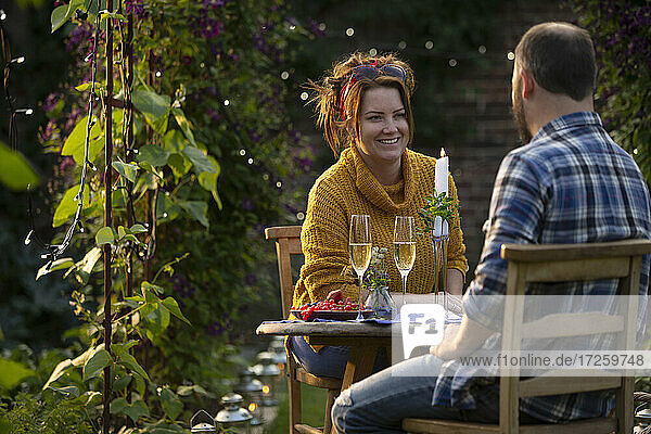 Glückliches Paar genießt Champagner am Gartentisch
