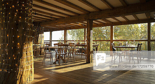 Holztische und Stühle im sonnigen leeren Restaurant